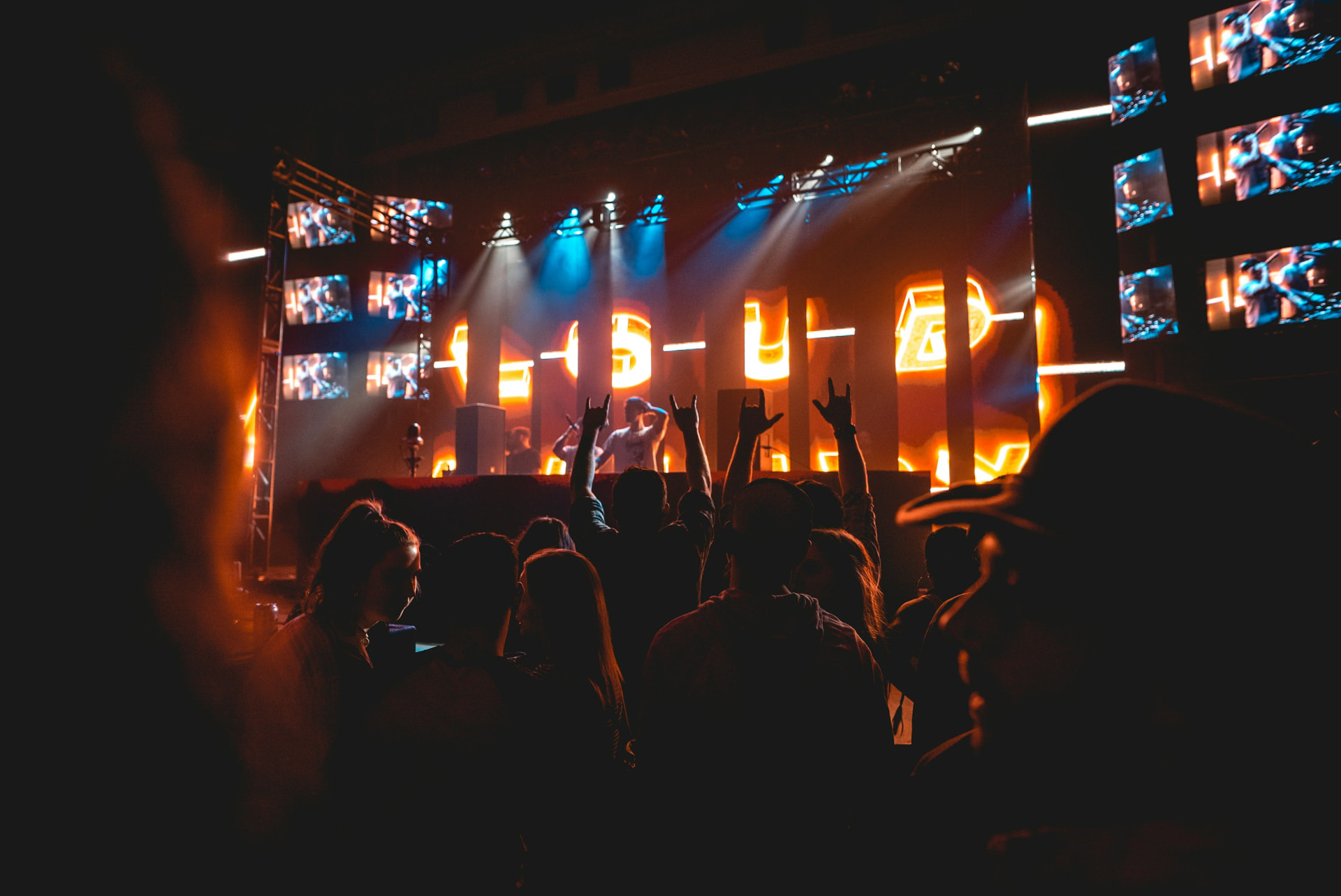 Concert crowd with raised hands in front of a lit stage